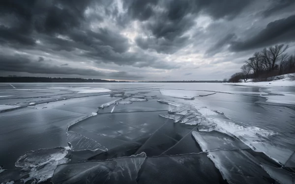 A serene view of a frozen lake, featuring cracked ice under a dramatic, cloud-filled sky. This HD desktop wallpaper captures winter's beauty and tranquility.