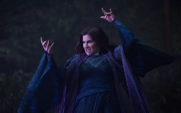 A dynamic HD wallpaper featuring Kathryn Hahn as she performs a captivating scene from the TV show Agatha All Along, showcasing her dramatic pose in a dark, mystical setting.