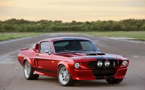 A classic Shelby GT500CR, showcasing its sleek red design, parked on an open road with a scenic background, captures the essence of vintage American muscle cars.