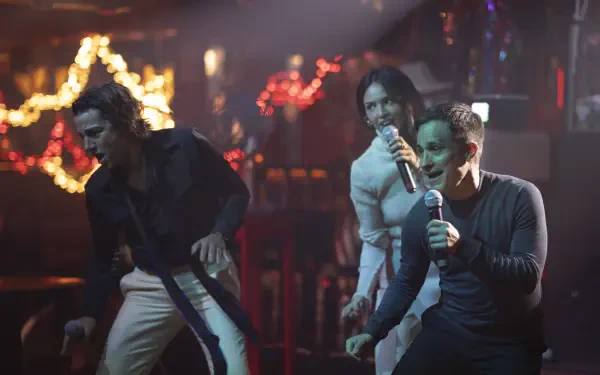 Dynamic scene from the TV show La Máquina (2024) featuring performers singing passionately on stage in a vibrant, illuminated setting.