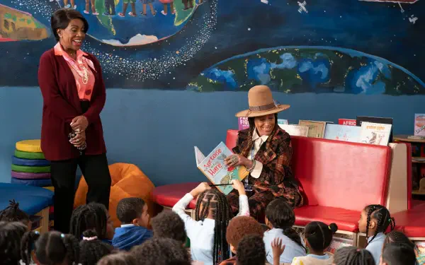 A scene from the TV show *Abbott Elementary*, featuring two teachers engaging with young students during storytime in a colorful classroom setting.