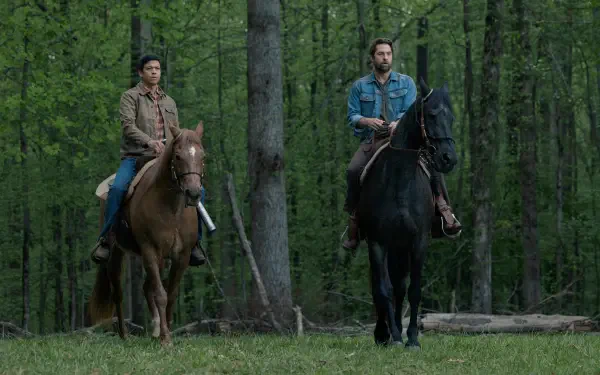 A scene from the TV show Teacup (2024), featuring Scott Speedman and another character, both on horseback in a lush green forest setting. 8K Ultra HD quality.