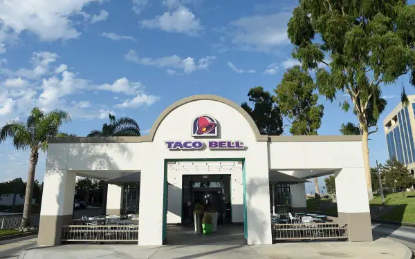 A bright, inviting Taco Bell restaurant with palm trees and a blue sky in the background, captured as a high-definition desktop wallpaper.