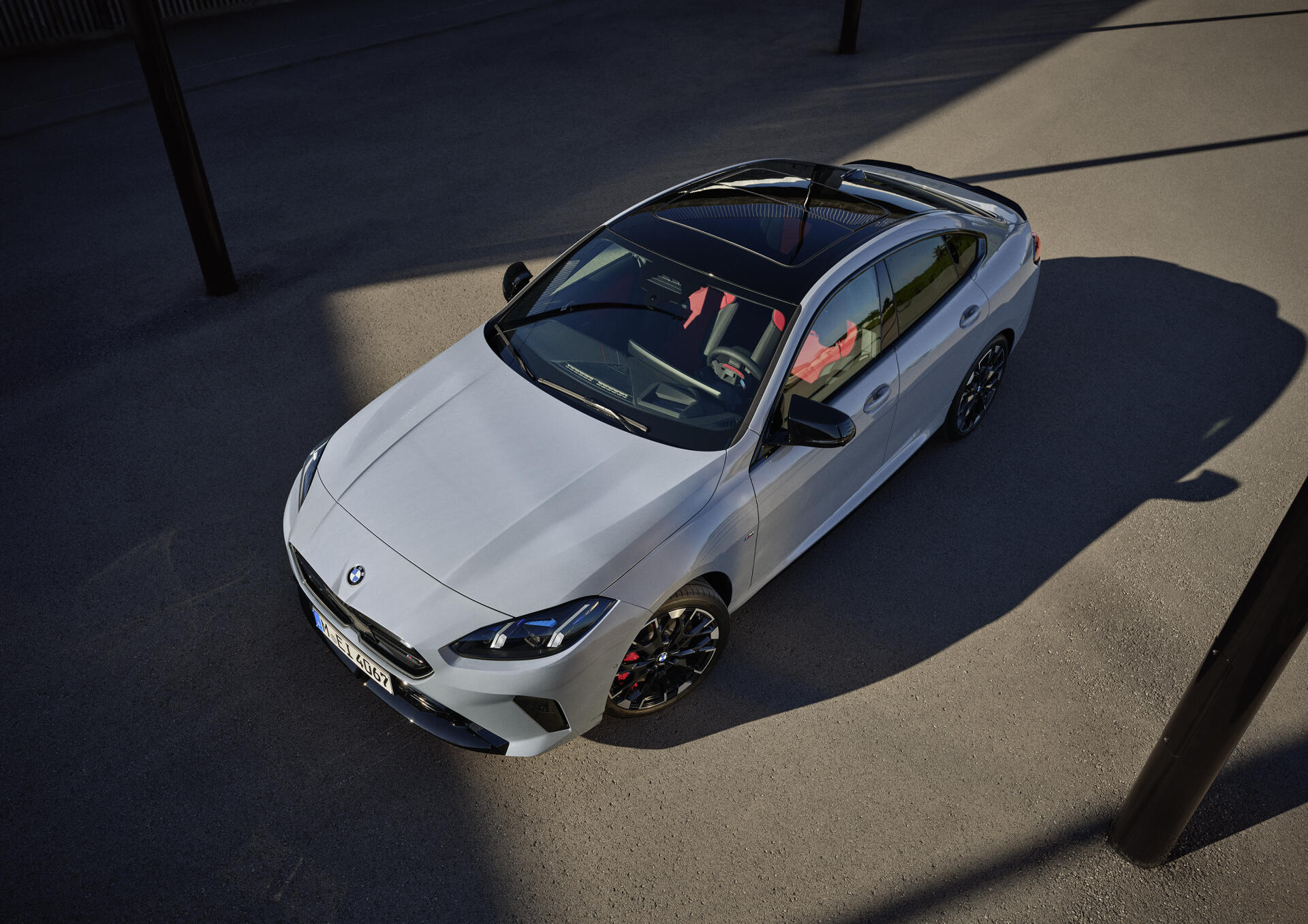 A sleek BMW M235 Gran Coupe stands in the spotlight, showcasing its modern design and stylish details, making for a striking HD desktop wallpaper and background.