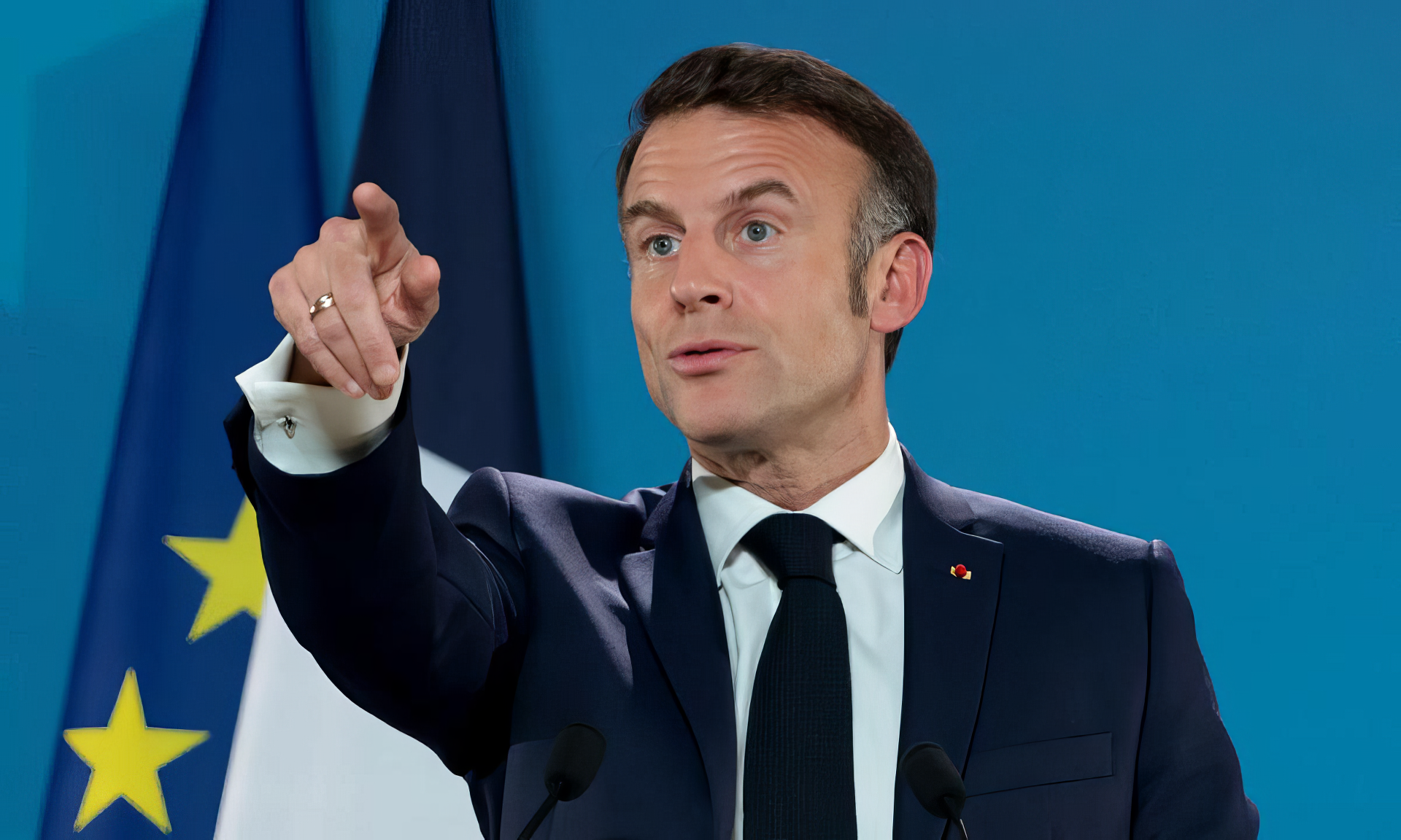 Emmanuel Macron gestures during a speech, with the French flag in the background. This high-definition image serves as a striking desktop wallpaper and background.