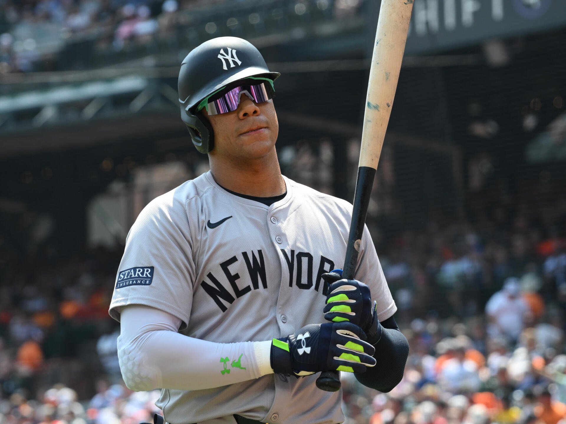 A New York Yankees player, wearing gray team uniform and sunglasses, stands with a baseball bat. This HD wallpaper captures the intensity of MLB action.