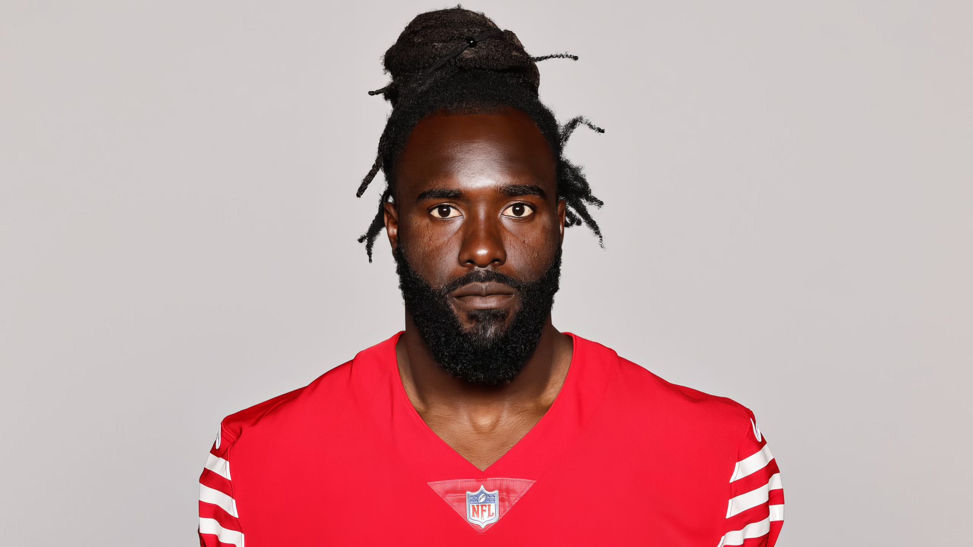 De'Vondre Campbell of the San Francisco 49ers poses in a bold red jersey, showcasing his intense expression, capturing the spirit of NFL football. High-definition wallpaper for fans.