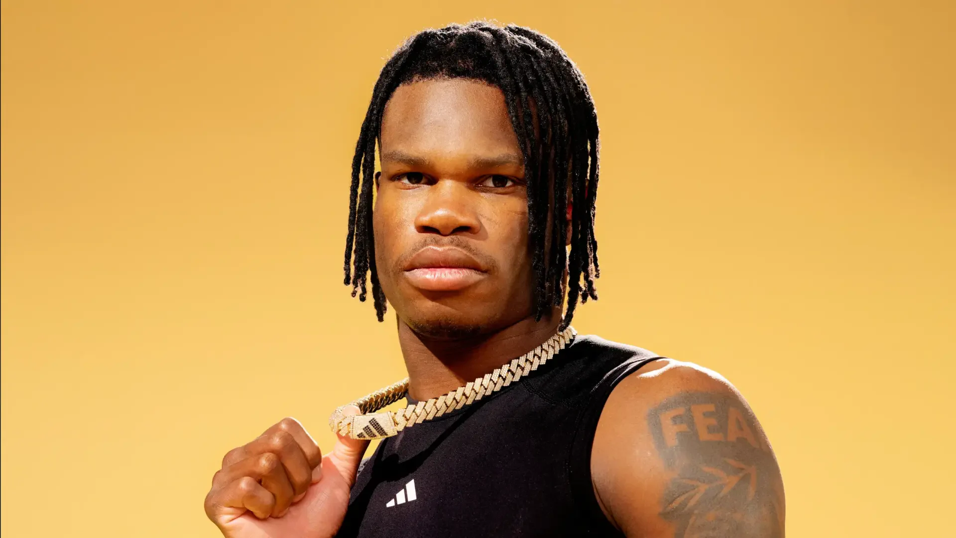 HD desktop wallpaper featuring Travis Hunter, showcasing his confident pose against a vibrant yellow background, highlighting his athletic style and expressive demeanor.