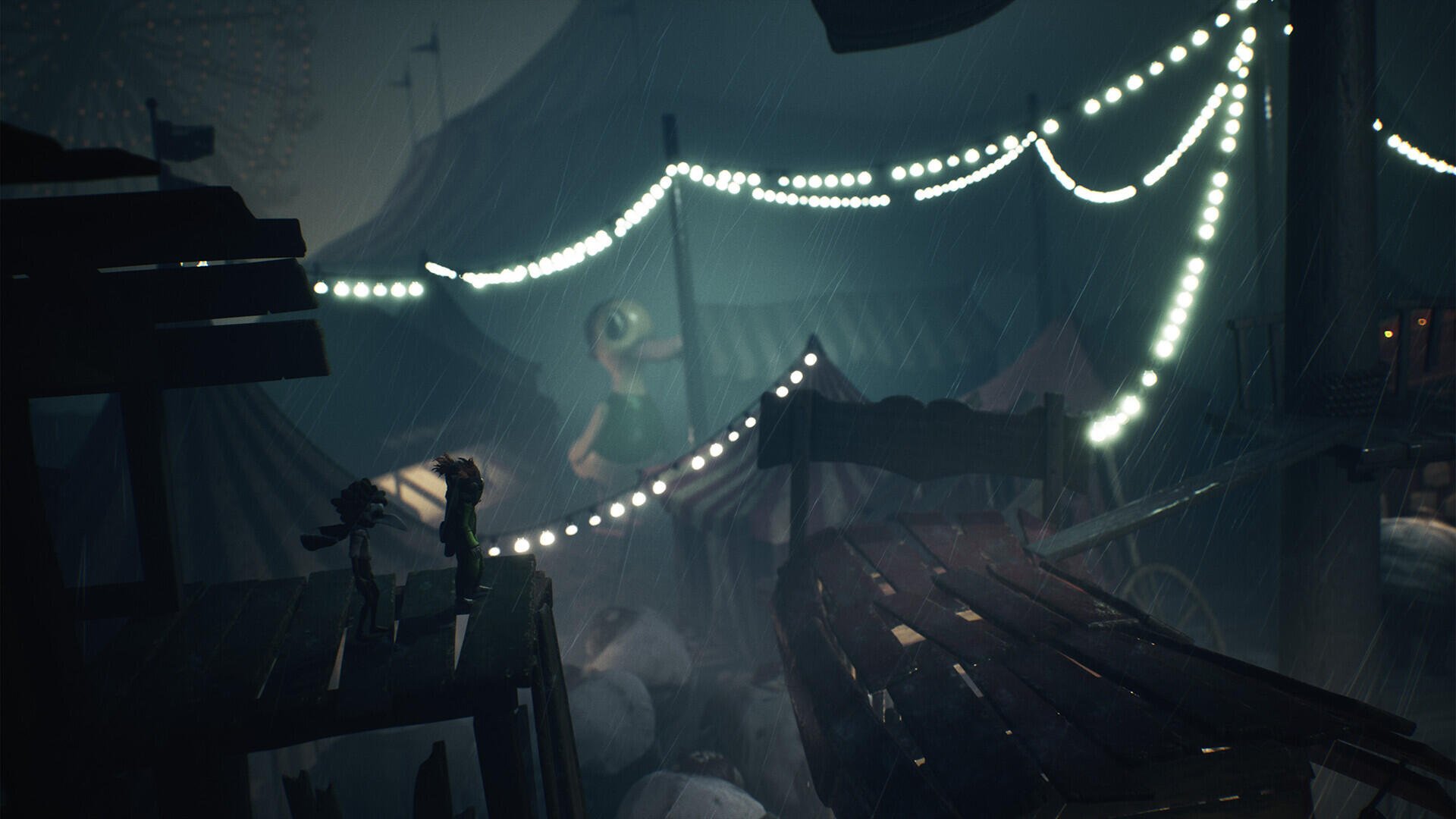 A dark and atmospheric scene from Little Nightmares III, featuring eerie lighting with strings of lights and a mysterious figure amidst scattered debris, creating a haunting backdrop.