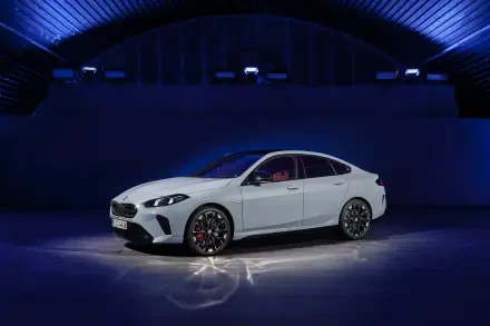 A sleek BMW M235 xDrive Gran Coupe showcased in a modern setting, featuring a striking white exterior and stylish alloy wheels, illuminated under dynamic blue lighting.