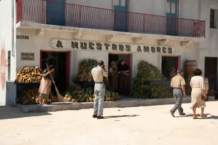 A vibrant scene featuring a market with lush fruits and vegetables. People engage in daily activities outside a building labeled A Nuestros Amores, reflecting a Queer cinematic aesthetic.