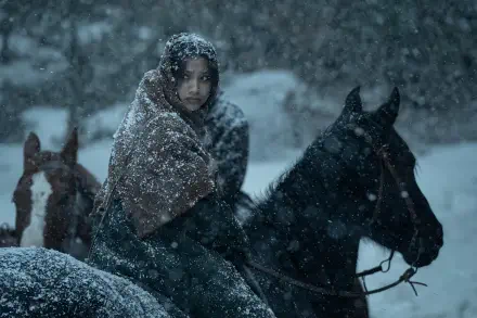 A snowy scene from the TV show American Primeval, featuring a figure in a warm cloak atop a horse, surrounded by a winter landscape. HD wallpaper for a striking backdrop.