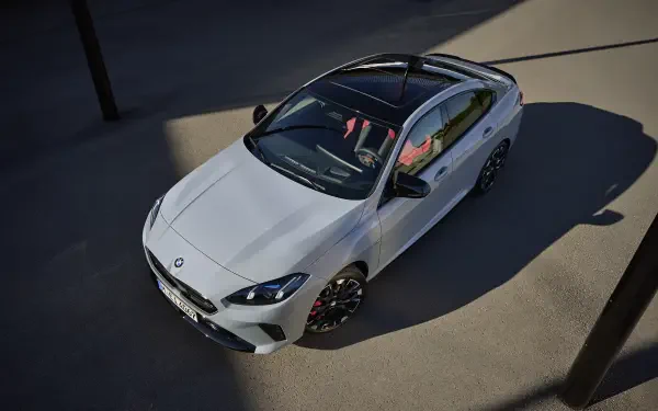 A sleek BMW M235 Gran Coupe stands in the spotlight, showcasing its modern design and stylish details, making for a striking HD desktop wallpaper and background.