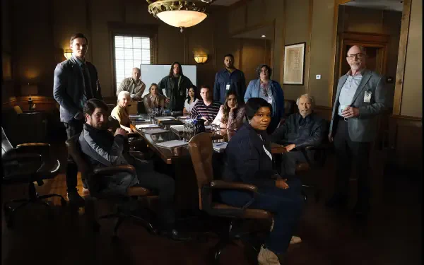 Group of jurors gathered around a conference table in a dimly lit room, from the movie Juror #2. A tense atmosphere captures their deliberation in this 4K Ultra HD wallpaper.