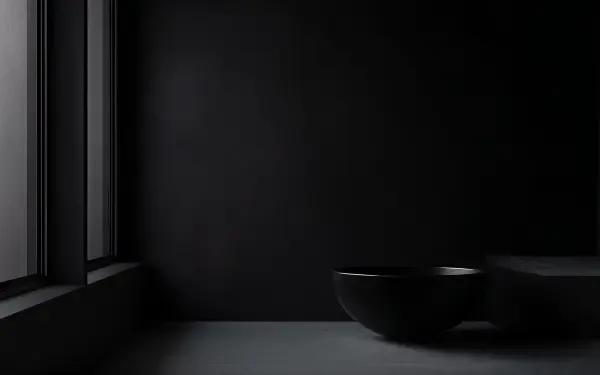A dark minimalist scene featuring a simple bowl on a smooth surface, illuminated by soft natural light from a window, rendered in 4K Ultra HD for a sleek desktop wallpaper.