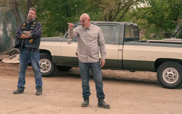 A scene from the TV show Tulsa King, featuring two characters standing near a vintage truck on a dirt road, evoking a gritty, dramatic atmosphere in this 4K Ultra HD wallpaper.