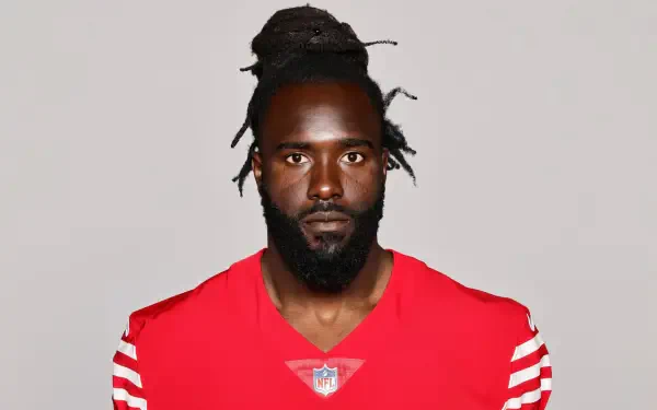 De'Vondre Campbell of the San Francisco 49ers poses in a bold red jersey, showcasing his intense expression, capturing the spirit of NFL football. High-definition wallpaper for fans.