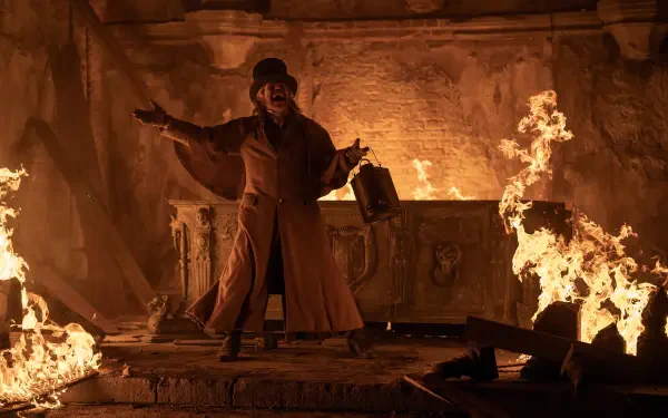 A dramatic scene from Nosferatu (2024) featuring Willem Dafoe amidst flames, set in a haunting, dimly lit environment. A striking 4K Ultra HD desktop wallpaper.