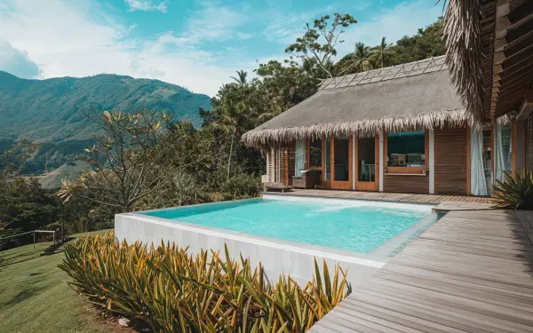 A serene spa scene featuring a beautifully designed structure with a pool, surrounded by lush greenery and mountains, captured in vibrant 4K Ultra HD detail.