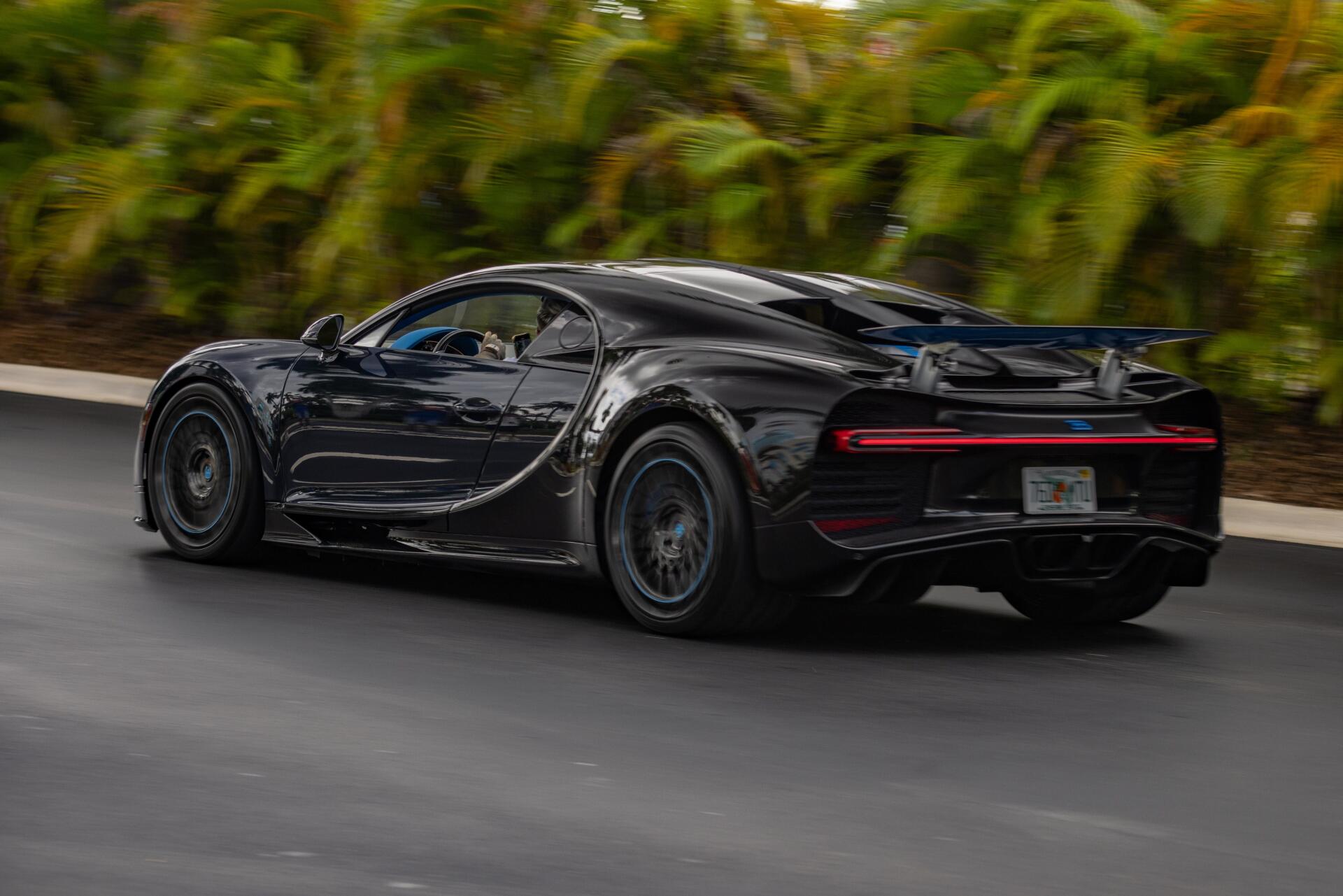 Sleek black Bugatti speeding on a road, captured in stunning 4K Ultra HD, making a dynamic PC desktop wallpaper and background.