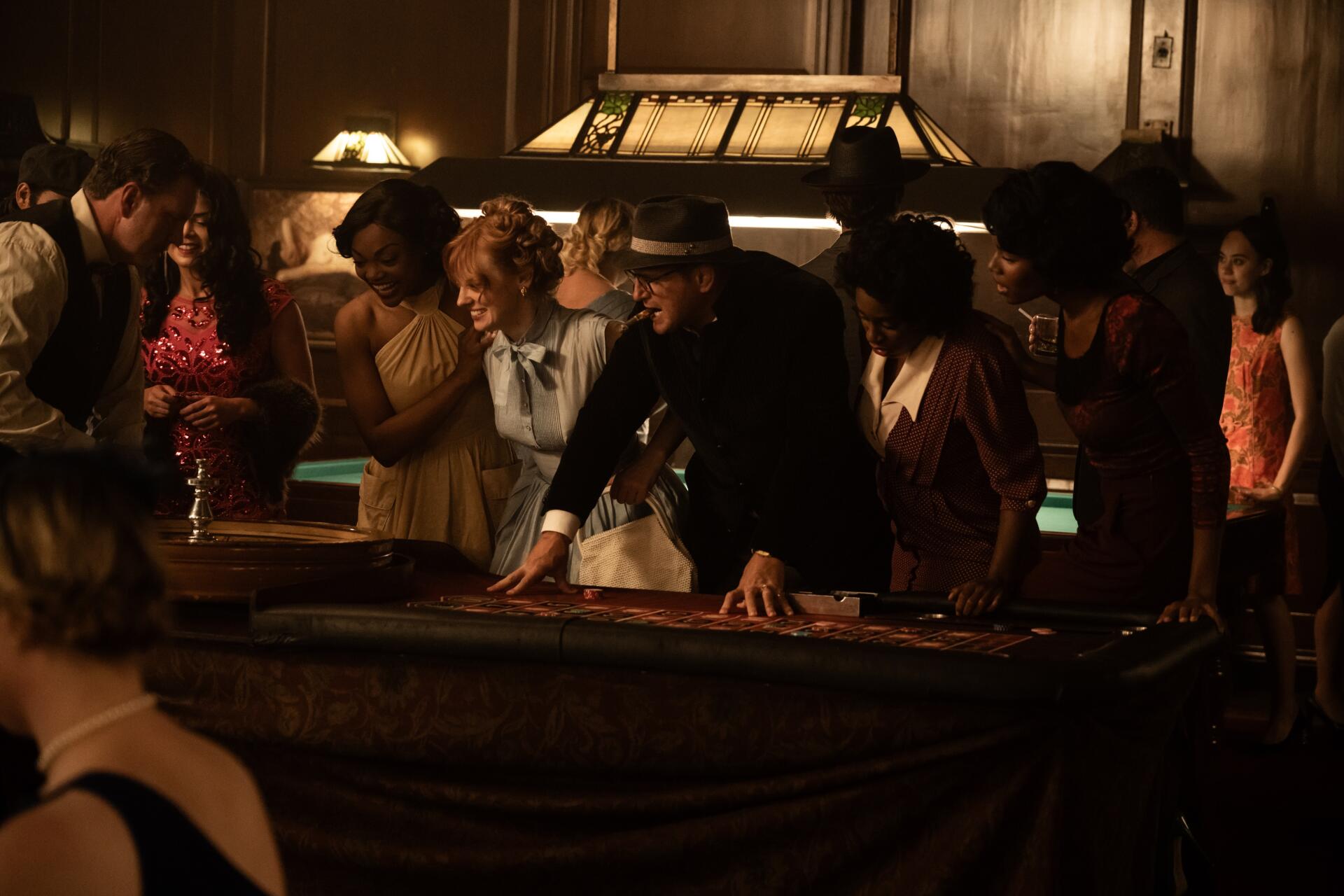 A scene from the movie Queen of the Ring, featuring a group of elegantly dressed individuals gathered around a casino table in a vintage setting. 4K Ultra HD desktop wallpaper.