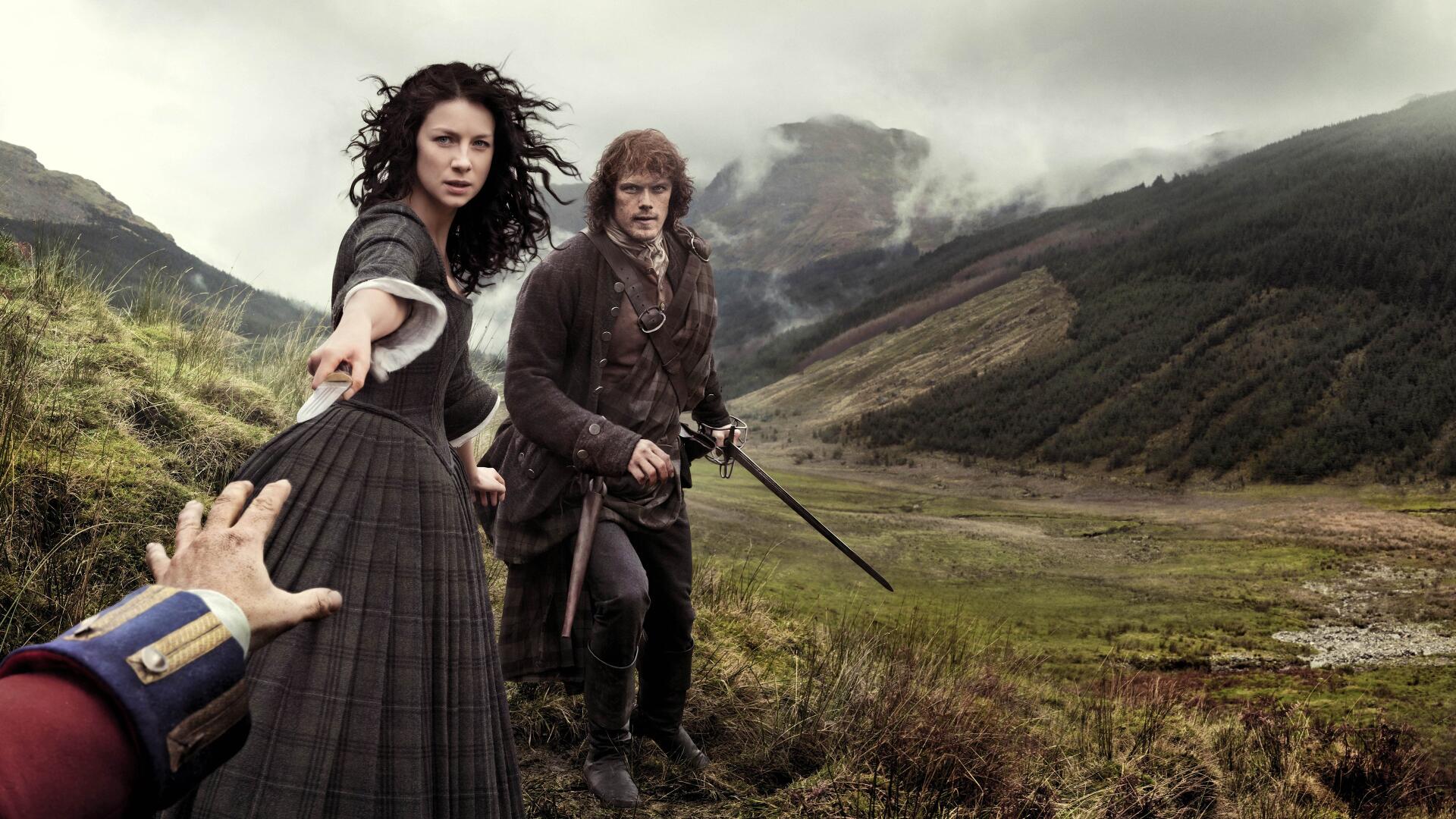 4K Ultra HD Outlander wallpaper featuring two characters in period clothing on a misty Scottish hillside, with one reaching out and the other holding a sword.