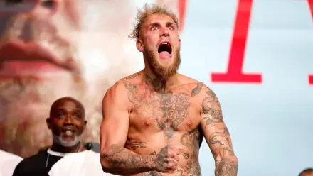 Jake Paul, a tattooed boxer, passionately celebrates with an intense expression, shirtless and ready for action, as part of a dynamic HD desktop wallpaper background.