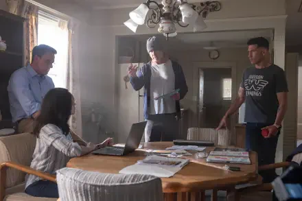 A scene from The Accountant 2, featuring four characters engaged in a tense discussion around a table in a well-lit kitchen. The image is a 4K Ultra HD desktop wallpaper.