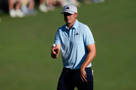 A golfer in an Adidas cap and light blue shirt holds a golf ball, standing on a green field. The image captures the essence of sports and golf in stunning 4K Ultra HD.