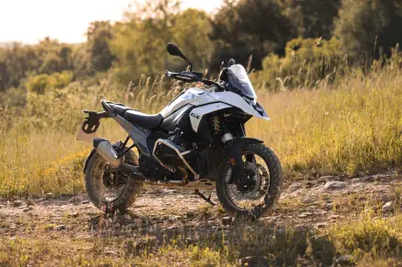 A BMW R1300GS motorcycle parked on rugged terrain, surrounded by tall grass, showcasing its adventurous design in a warm outdoor setting, captured in stunning 4K Ultra HD.