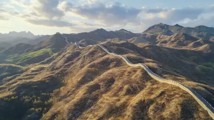 A stunning HD desktop wallpaper showcasing the Great Wall of China winding through rugged mountainous landscape under a partly cloudy sky.