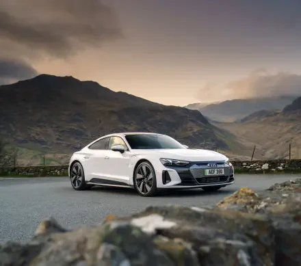 White Audi E-Tron GT Quattro electric car parked on a mountain road under a cloudy sky, captured in stunning 4K Ultra HD.