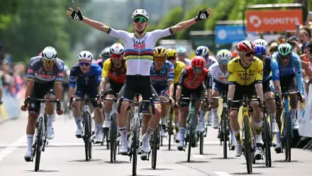 HD desktop wallpaper capturing the intense finish of a Critérium du Dauphiné cycling race with riders sprinting on a road under clear skies.