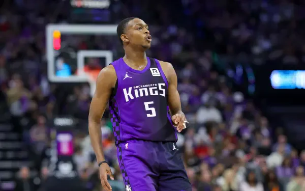De'Aaron Fox of the Sacramento Kings on the court, wearing a purple jersey with the number 5. The vibrant background is filled with a cheering crowd, capturing the excitement of NBA basketball.