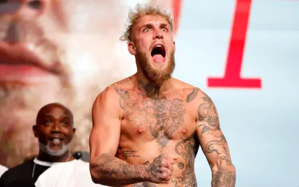Jake Paul, a tattooed boxer, passionately celebrates with an intense expression, shirtless and ready for action, as part of a dynamic HD desktop wallpaper background.