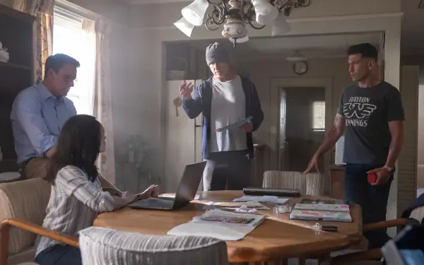 A scene from The Accountant 2, featuring four characters engaged in a tense discussion around a table in a well-lit kitchen. The image is a 4K Ultra HD desktop wallpaper.