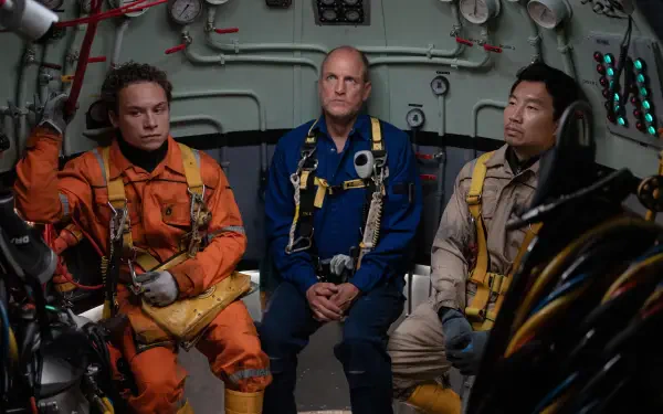Three men in diving suits sit inside a futuristic vessel, showcasing a tense moment from the movie Last Breath (2025) featuring Finn Cole, Woody Harrelson, and Simu Liu.