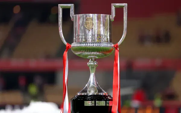 A close-up of the Copa del Rey trophy, featuring silver details and red ribbons, set against a blurred stadium background. This HD image serves as a dynamic soccer-themed desktop wallpaper.