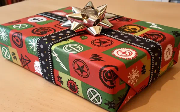 Christmas present wrapped in red and green paper with festive symbols, topped with a silver bow, captured in sharp 4K Ultra HD for PC desktop wallpaper.