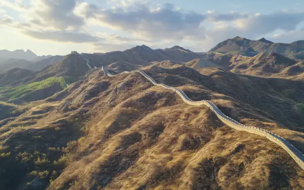 A stunning HD desktop wallpaper showcasing the Great Wall of China winding through rugged mountainous landscape under a partly cloudy sky.