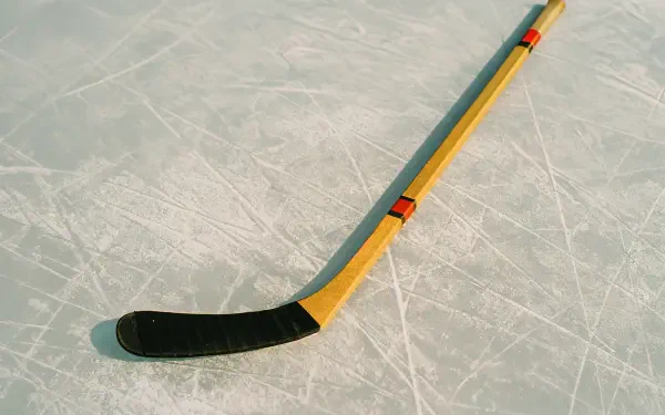 4K Ultra HD desktop wallpaper featuring a yellow and black hockey stick resting on a textured ice surface.