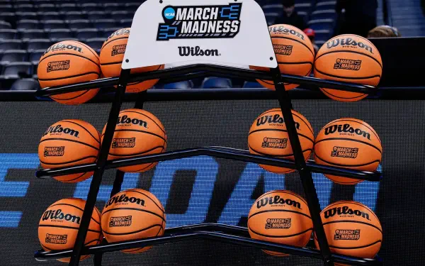 HD basketball wallpaper showing an NCAA March Madness rack filled with Wilson basketballs on a court background.