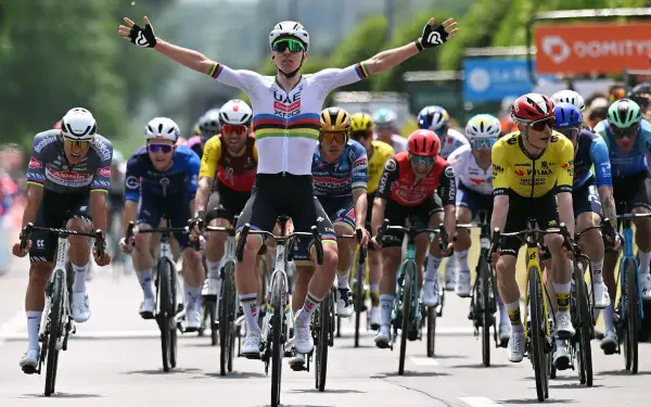 HD desktop wallpaper capturing the intense finish of a Critérium du Dauphiné cycling race with riders sprinting on a road under clear skies.