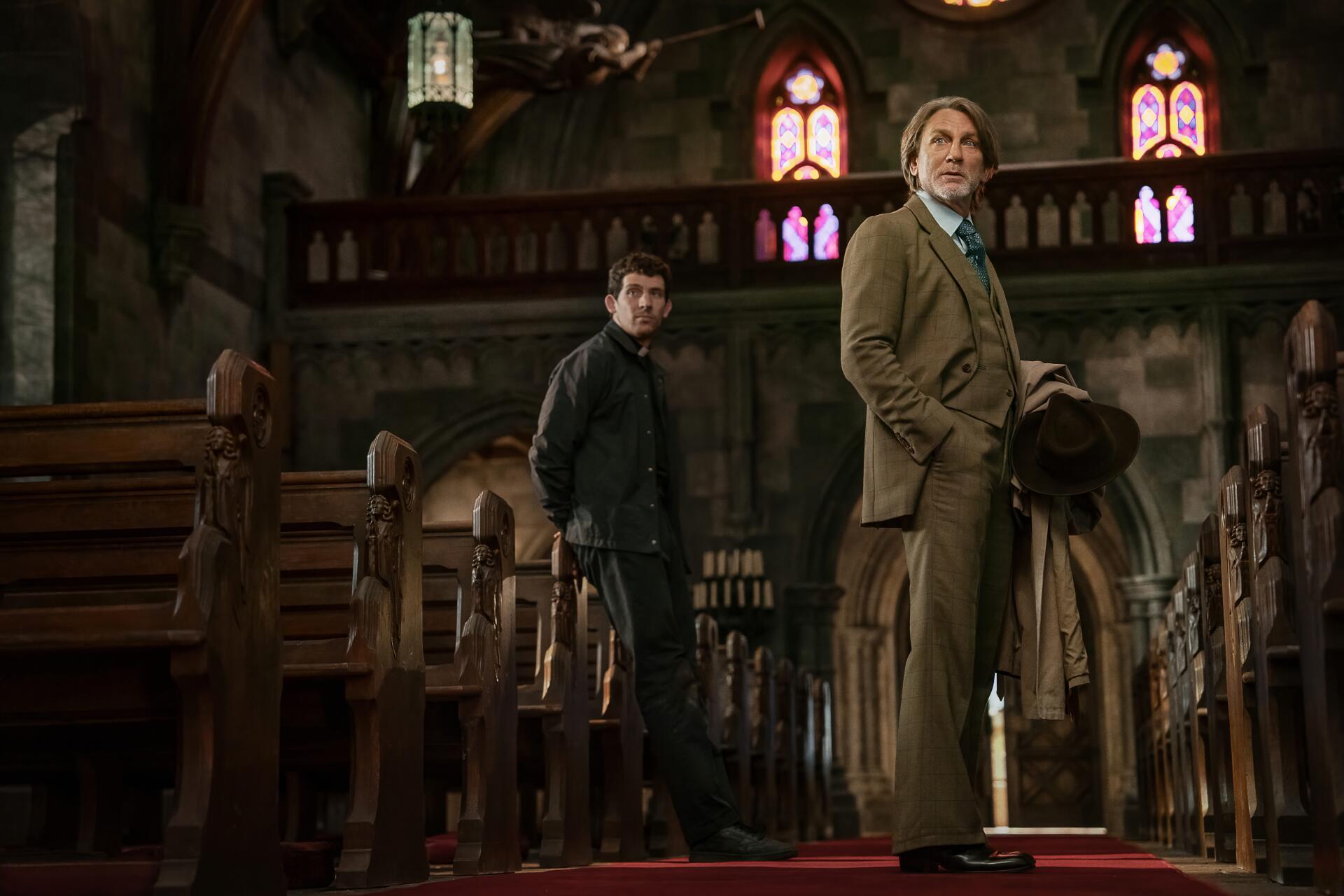 8K Ultra HD PC desktop wallpaper and background from the movie Wake Up Dead Man: A Knives Out Mystery — two coat‑clad figures stand among wooden pews in a dim, stained‑glass church interior.
