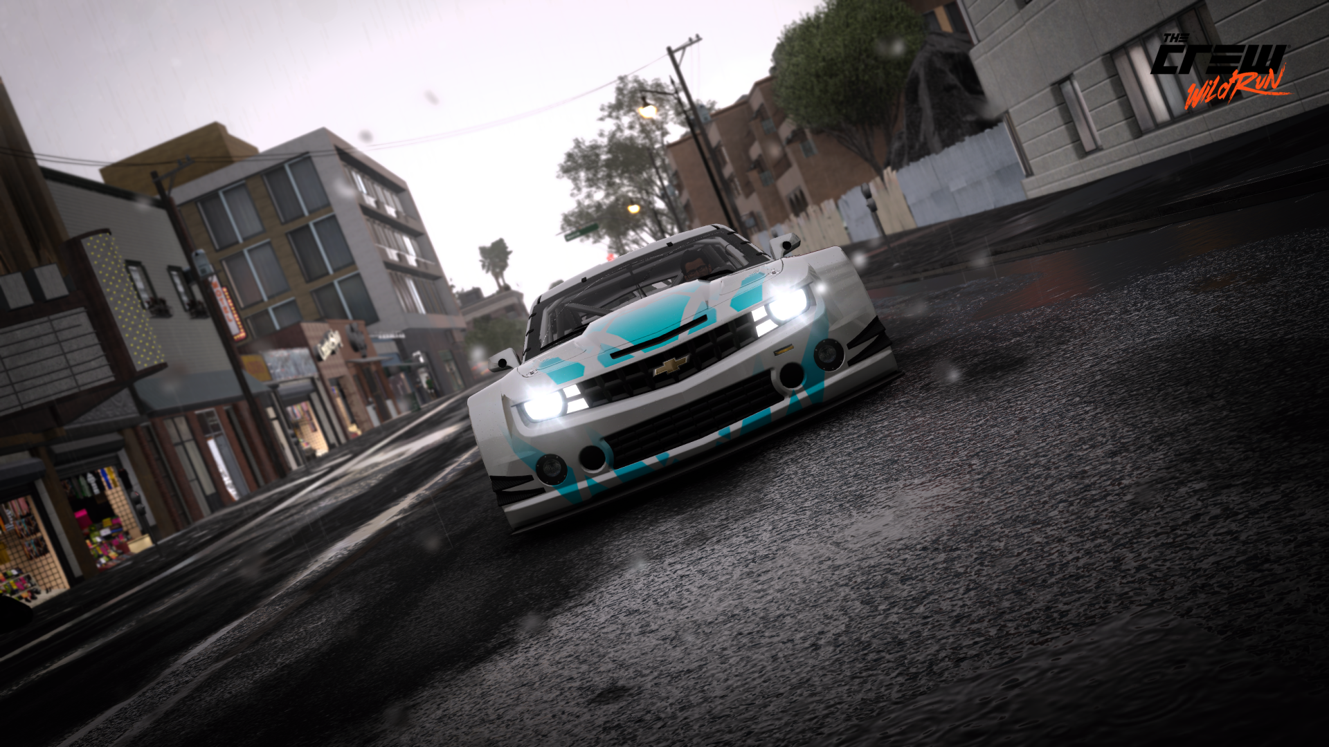 Low-angle Chevrolet Camaro racing through a rainy city circuit, wet reflections and motion blur — 2K Quad HD PC desktop wallpaper from The Crew.