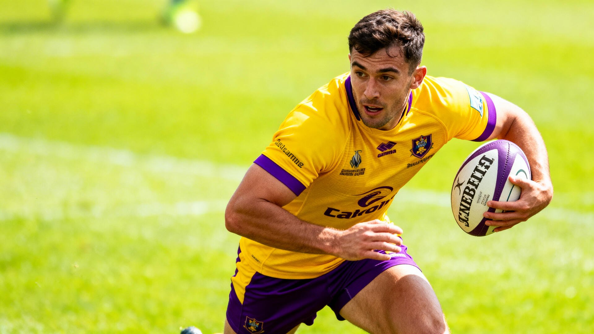 Rugby player in a yellow jersey sprinting with the ball across a sunlit grass field — 4K Ultra HD PC desktop wallpaper background.