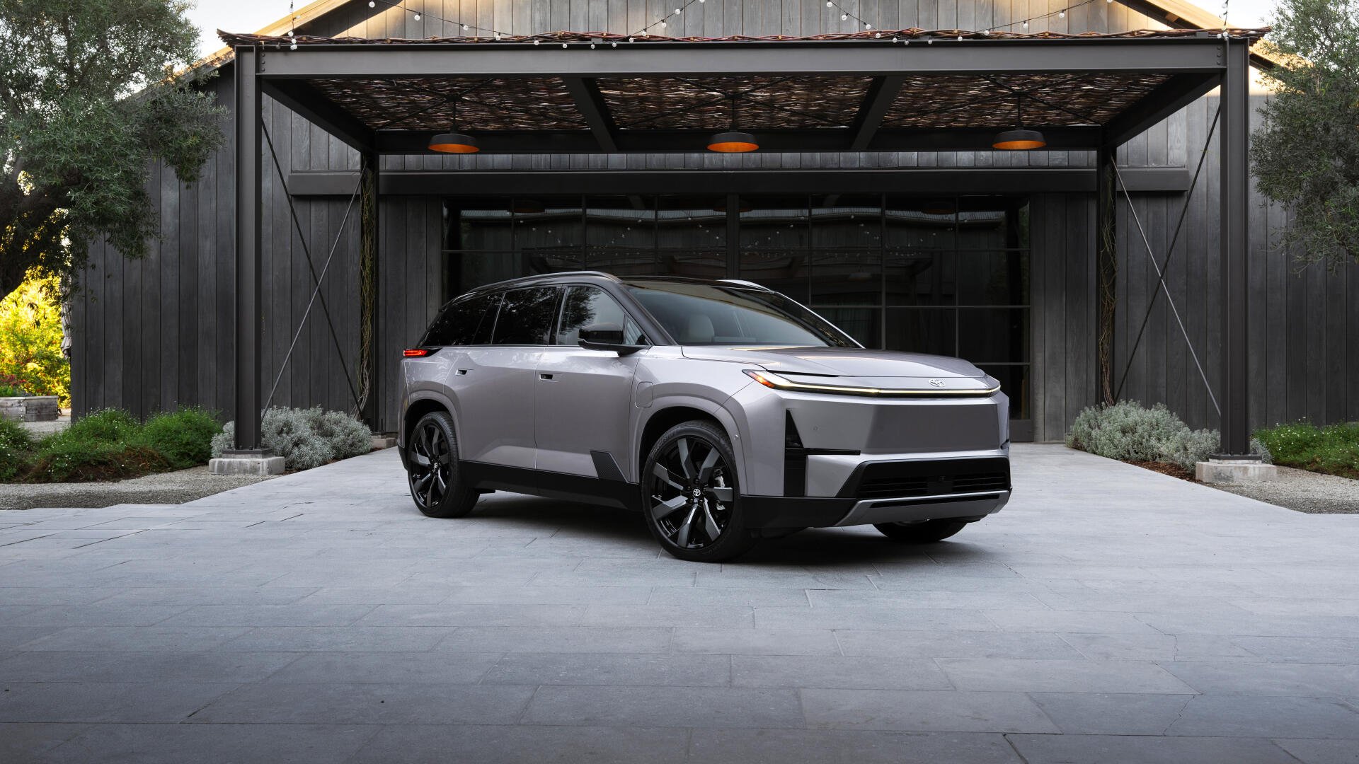 Gray Toyota Highlander BEV parked under a modern carport, sleek wheels and LED accents — 4K Ultra HD PC desktop wallpaper of a Toyota electric vehicle.