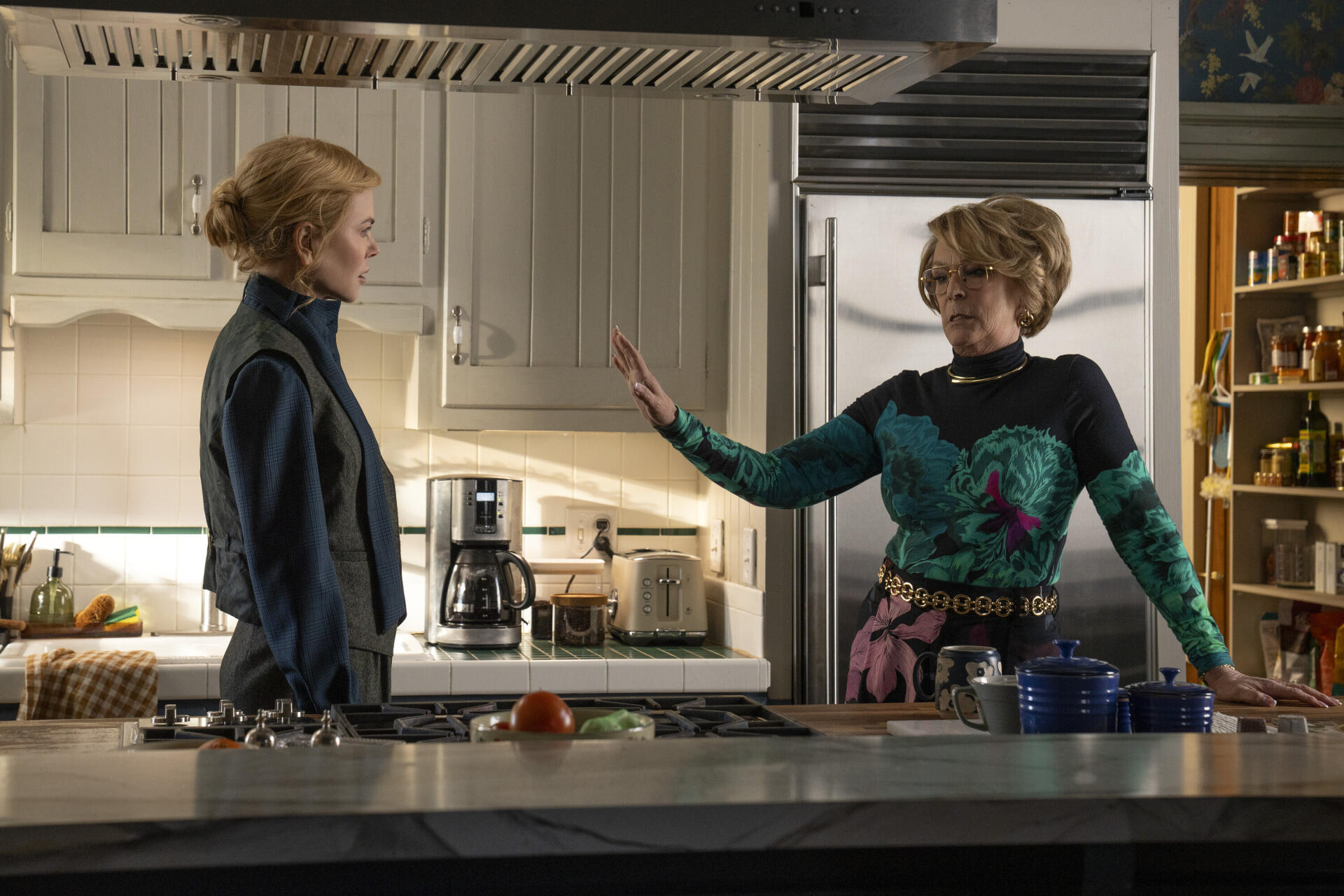 2K TV-show desktop wallpaper: scene from Scarpetta—two women in a modern kitchen, one gesturing toward the other during a tense conversation.