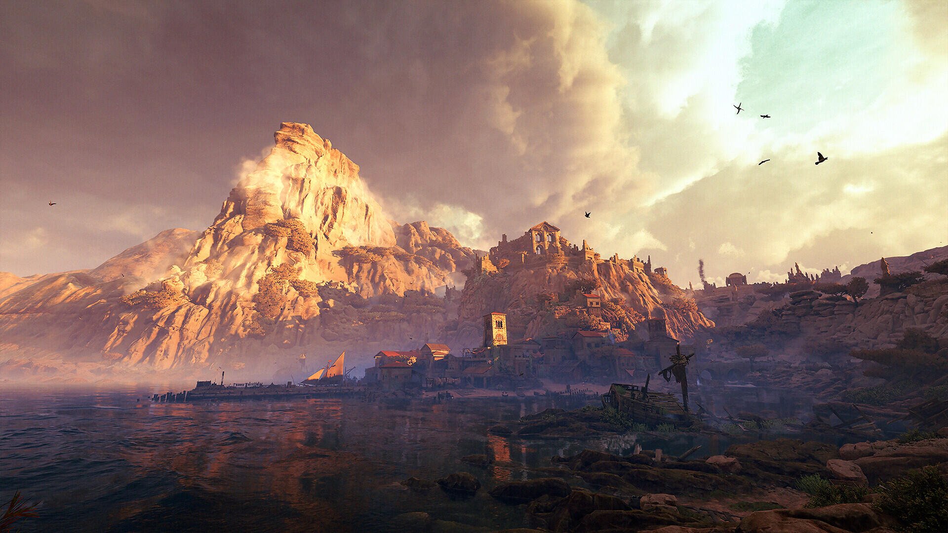 GreedFall: The Dying World video game HD PC desktop wallpaper: sunlit mountain and coastal village ruins by the shore under a dramatic sky with flying birds.