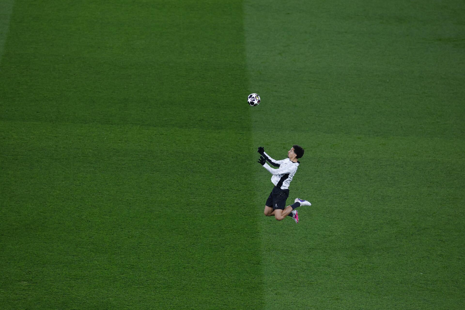 4K Ultra HD desktop wallpaper: overhead shot of a Paris Saint-Germain F.C. player leaping to head the ball during a UEFA Champions League match on a vivid green pitch.